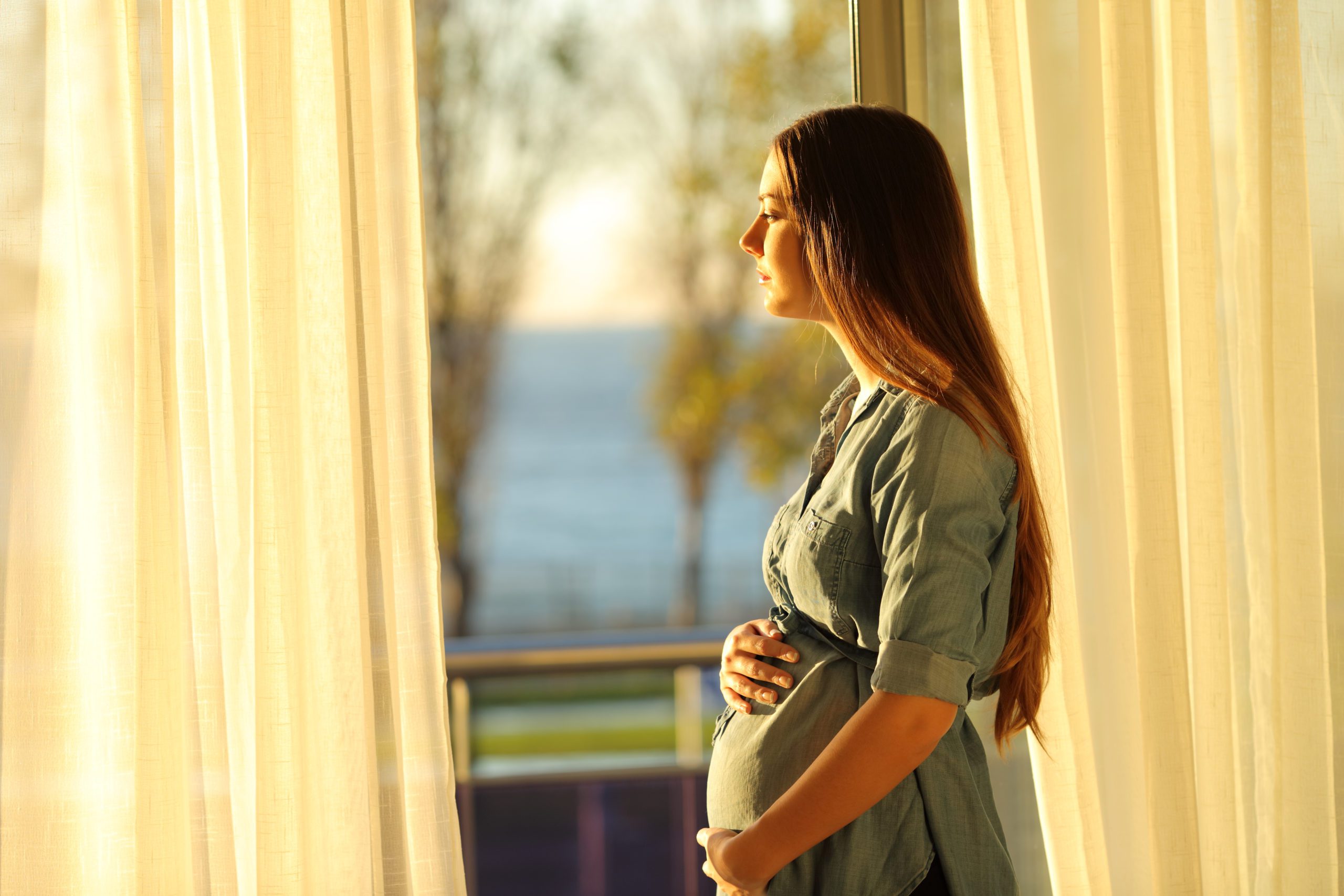 Side View Portrait Of A Serious Pregnant Woman Looking Through A